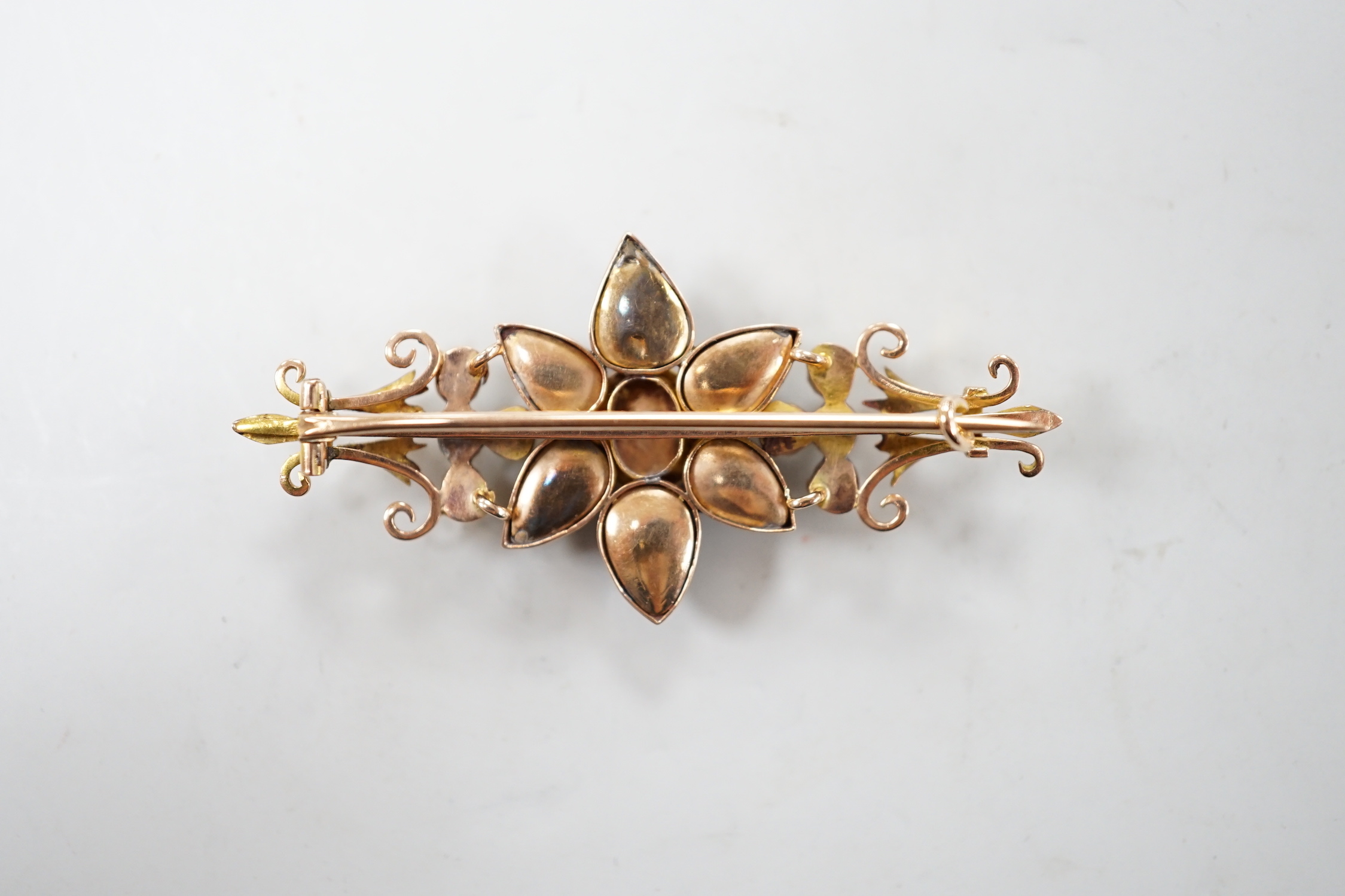 A late Victorian yellow metal, foil backed garnet and split pearl set flower head bar brooch, 55mm, gross weight 7.9 grams.